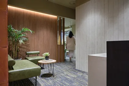 Reception corridor with walnut paneling and green lounge seating
